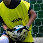 Un niño con un peto amarillo sujeta el balón con el cuerpo