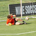 Una portera de fútbol realizando una caida lateral y escapándosele el balón