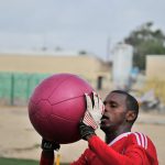 Un portero sosteniendo en las manos un balón medicinal grande