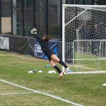 Una portera realizando una estirada durante un entrenamiento.
