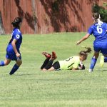 Una portera de fútbol realizando una parada frontal rasa con caida.
