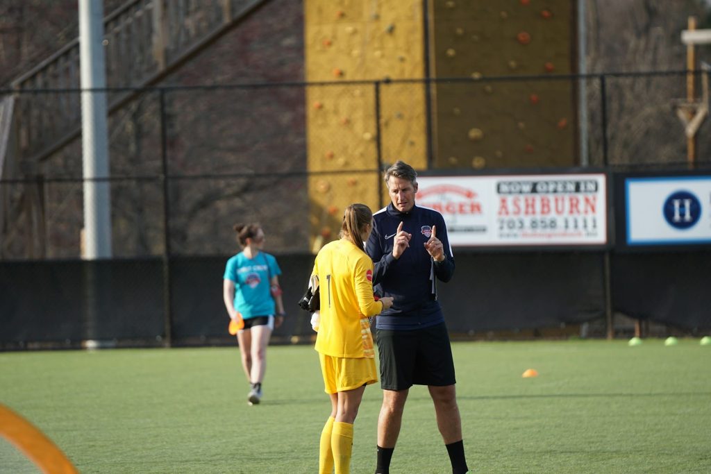 Entrenador hablando con una portera de fútbol.