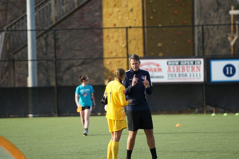 Entrenador hablando con una portera de fútbol.
